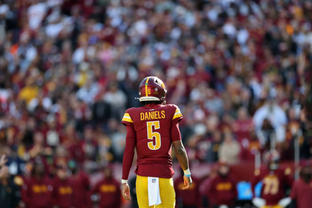 Quarterback Jayden Daniels #5 of the Washington Commanders looks on during the first half against the Dallas Cowboys at Northwest Stadium o